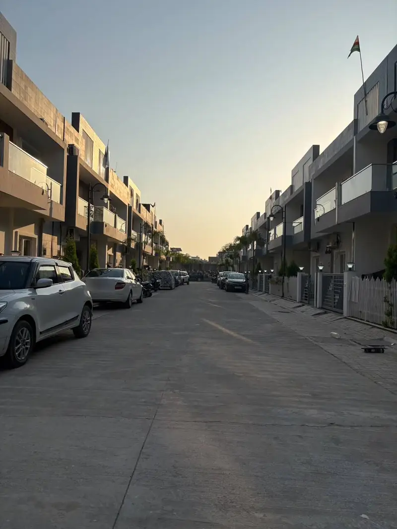 Street at sunset inside JHM Aura, with duplex row-houses on both sides